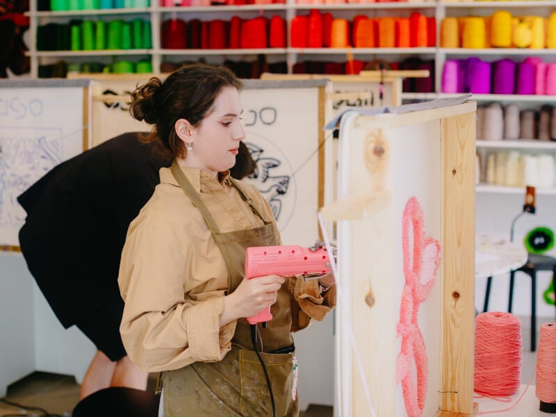 Woman using a tufting gun in a rug tufting class